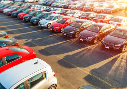 Parking lot of cars with sun shining in background